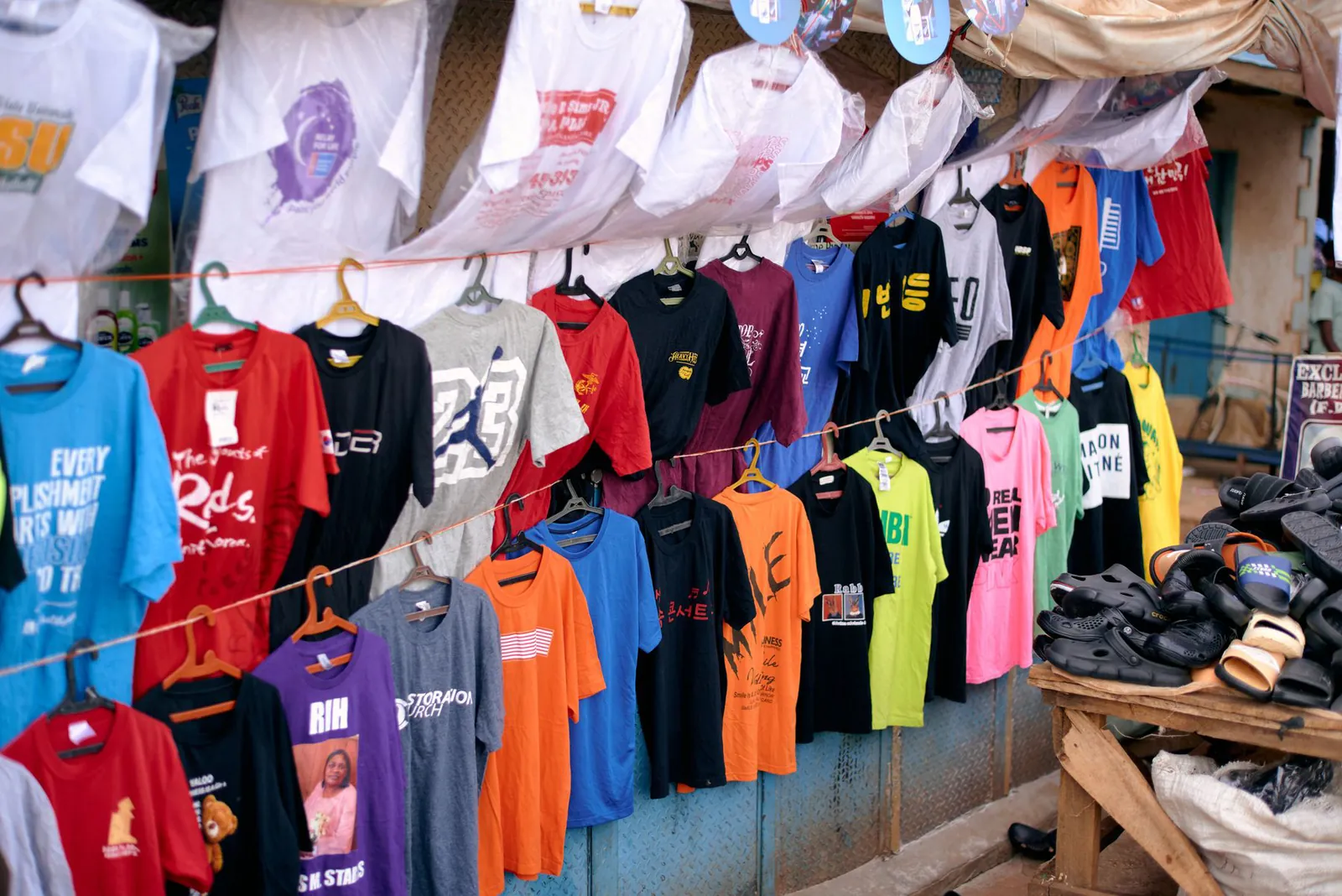 Puesto de mercado con polos de colores colgados en ganchos