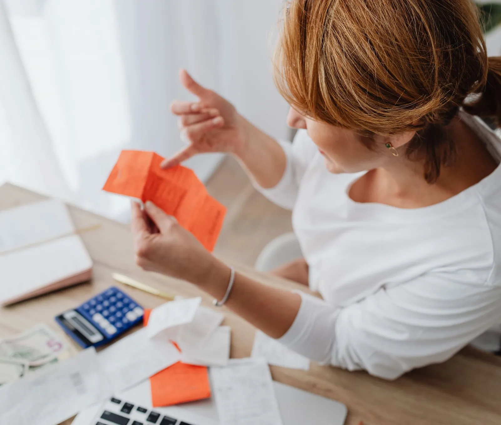 Mujer revisando boletas junto a una calculadora y billetes