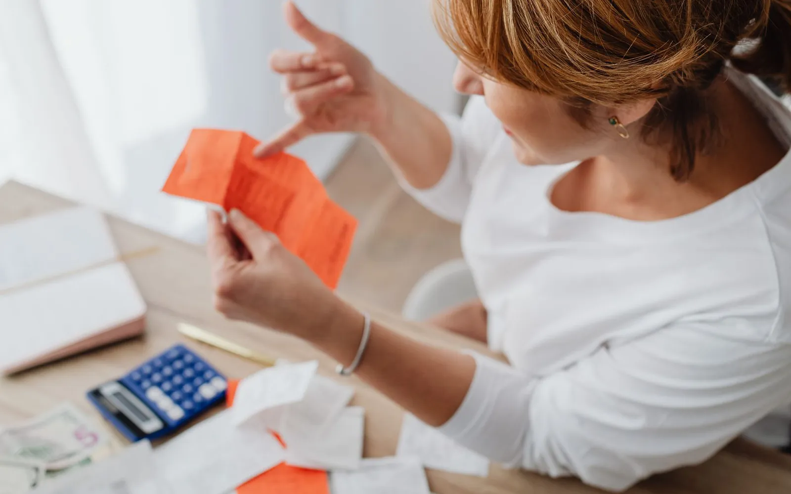 Mujer revisando boletas junto a una calculadora y billetes